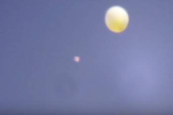 Светящийся НЛО изучает летящий шар